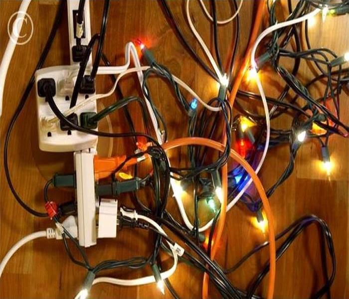 extension cords with many cords plugged in and holiday lights plugged in  